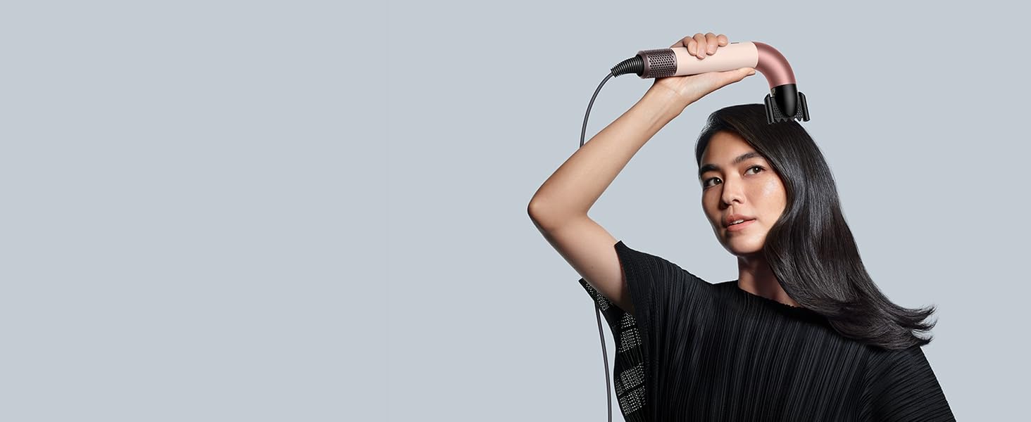 Le Dyson Supersonic r et l’embout lissant utilisés par un mannequin pour réduire les frisottis.