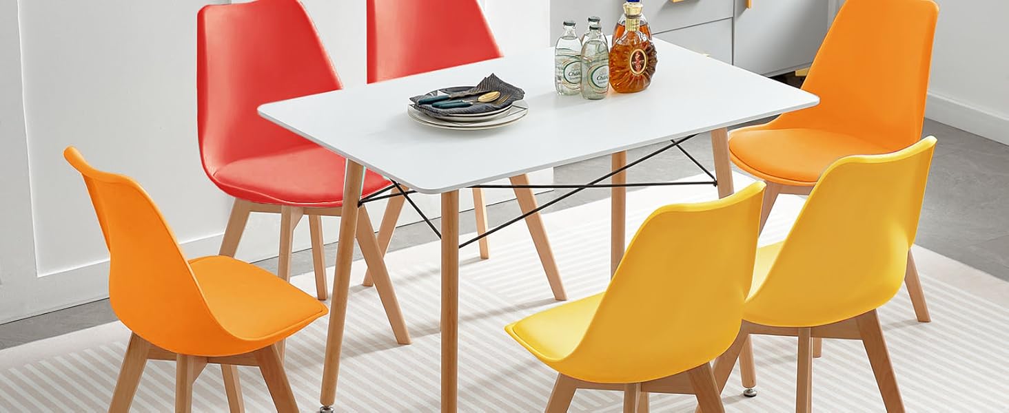 avec table rectangulaire blanche et six chaises avec sièges moulés orange et rouge éclatants avec pieds en bois, disposés sur un tapis gris à motifs