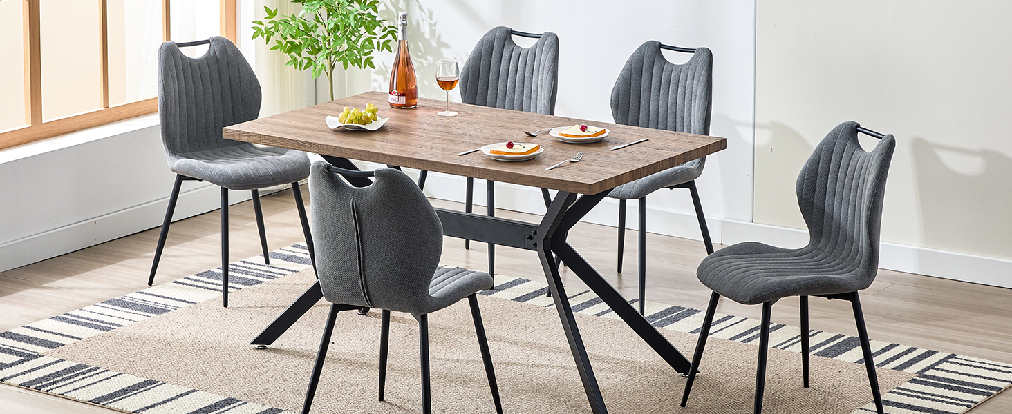 avec table en bois rustique et quatre chaises rembourrées grises. Plante d'intérieur et décoration sur la table, tapis à motifs en dessous